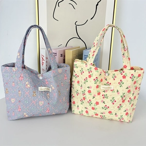 Detailed close-up of quilted floral fabric texture and snap button on tote bag