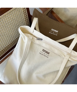 Detail of minimalist canvas tote bags with secure zipper and logo in olive and cream