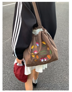 Close-up of mushroom embroidery and leaf patterns on a dark brown nylon tote bag