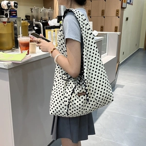 Polka dot canvas tote bag with front pocket shown in a lifestyle commuter scene