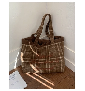 Detail of vintage brown plaid tote bag featuring red embroidery on corduroy texture