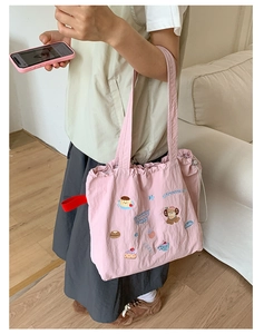 Pink fabric tote bag featuring cute cartoon embroidery and adjustable drawstring closure