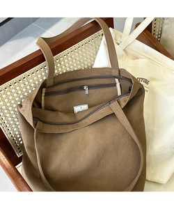 Detail of canvas tote bag showing metal zipper pocket and thick fabric texture