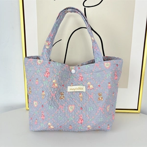 Detail view of purple quilted handbag with cute rabbit and bear patterns and soft handles