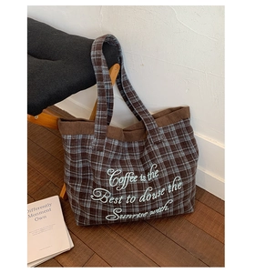 Detailed texture of plaid wool tote bag with corduroy trim and cursive embroidery