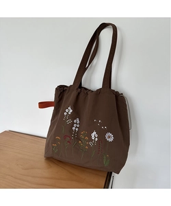 Macro view of detailed floral embroidery on a dark brown nylon vintage tote bag