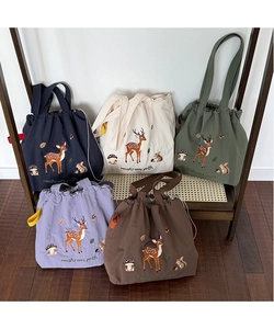 Detail of five canvas tote bags with forest embroidery and drawstring closure