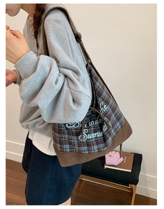 Detail view of large plaid canvas tote featuring artistic blue lettering and corduroy base