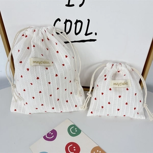Vertical striped white drawstring bags with red heart patterns and brand woven label