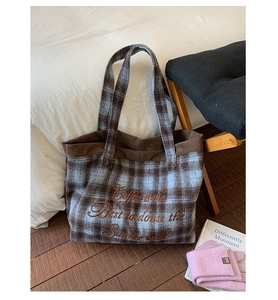 Detail of embroidered plaid tote bag with brown corduroy trim and textile texture
