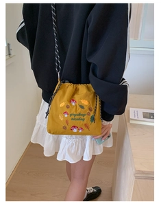 Detail of cute mustard yellow nylon crossbody bag with mushroom embroidery and strap