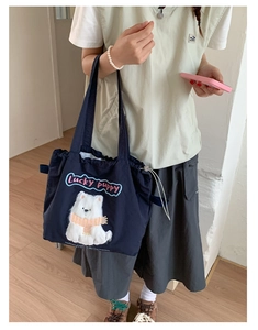 Close-up of the navy canvas tote bag featuring an embroidered lucky puppy cartoon design