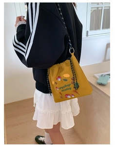 Detail of yellow nylon crossbody bag with mushroom embroidery and woven drawstring strap