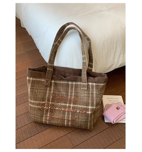 Detail of embroidered quote on brown plaid wool tote bag with corduroy edge