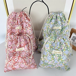 Detail of four floral fabric drawstring storage bags with cotton ropes and woven labels