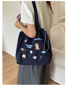 Close-up of navy blue drawstring tote bag with cute cartoon pudding puppy embroidery