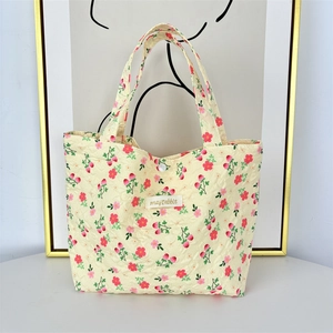 Close-up of floral quilted tote bag featuring strawberry patterns and top button closure