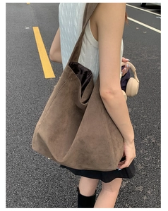 Close-up of a large brown suede tote bag with matte texture worn on the shoulder