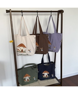 Detailed embroidery of mushroom house and rabbit on colorful canvas tote bags