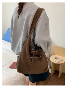 Close-up of brown corduroy shoulder bag with Bonne journée embroidery and drawstring bow