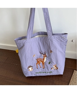 Detail of light purple canvas tote with forest animal embroidery and drawstring side