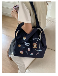 Detail of navy canvas tote bag featuring cute cartoon puppy embroidery and white drawstring