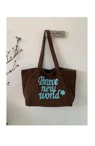 Detail of brown corduroy tote bag with blue Brave New World embroidery and plaid lining