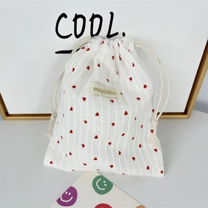 Detailed view of the red heart pattern and vertical stripe texture on a drawstring pouch
