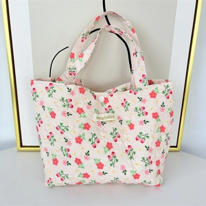 Detail of floral quilted lunch bag showing strawberry print and snap button closure