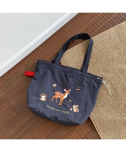 Detail of dark blue tote bag featuring forest animal embroidery and drawstring closure