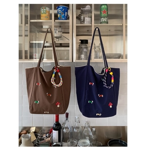 Detail of mushroom and dog embroidery on large canvas tote bags with woven charms