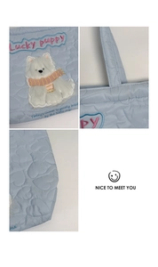 Detail of light blue heart quilted fabric with cute 3D puppy plush patch and embroidery