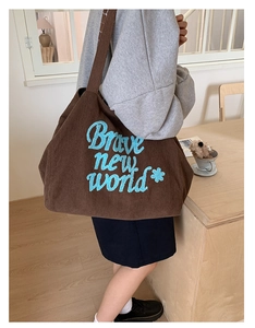 Detail of brown corduroy tote bag featuring blue Brave New World embroidery design