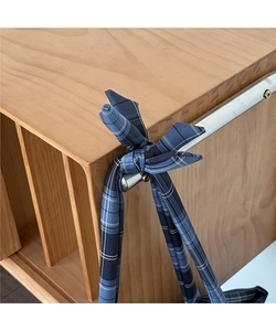 Détail de la bandoulière à carreaux bleus nouée en nœud sur un grand sac cabas