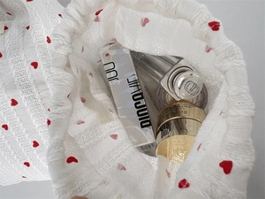 Top-down view of a vertical stripe heart drawstring storage bag filled with cosmetics