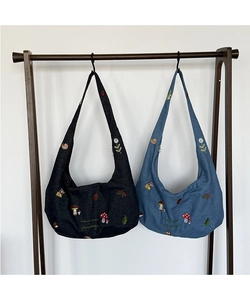 Détail de sacs en toile en forme de croissant avec broderie de forêt et champignons