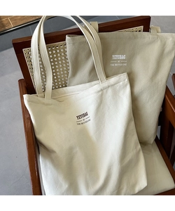 Detail of minimalist canvas tote bags with YEYUBAG letter print on a vintage chair