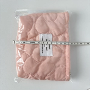 Pink quilted lipstick pouch with heart texture being measured at 13cm width