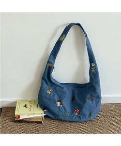 Détails de broderie de champignons et fleurs sur un sac croissant en toile bleue