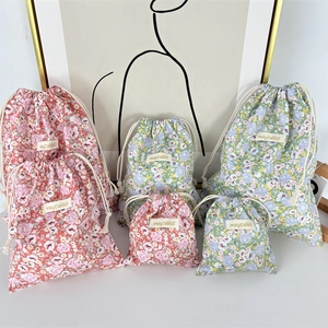 Detail view of cotton floral drawstring pouches in pink and green for travel storage