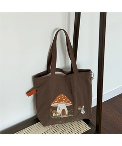 Detail of dark brown tote bag with mushroom house embroidery and into the woods text