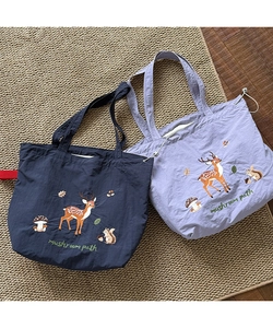 Detailed close-up of forest animal embroidery on navy and purple canvas tote bags