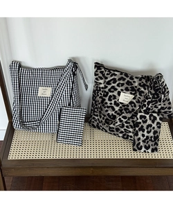 Detail view of large canvas tote bags in checkerboard and leopard patterns on a shelf