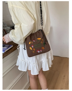 Detail of coffee nylon crossbody bag featuring colorful mushroom and acorn embroidery