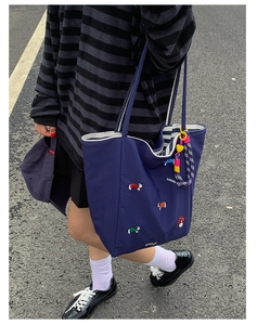Detail of navy canvas tote bag featuring mushroom embroidery and striped lining