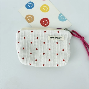 Close-up of striped makeup bag fabric with red heart patterns and brand label detail