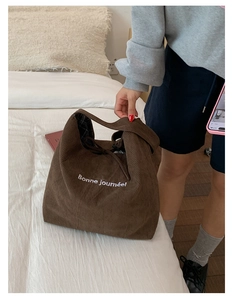 Close-up of brown corduroy tote bag with Bonne journée embroidery and checkered lining