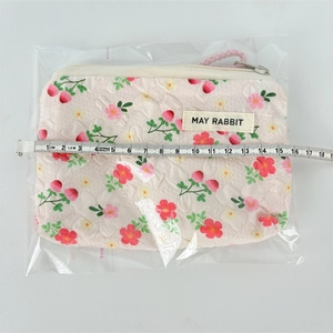 Close-up of floral mini canvas pouch with zipper and pink wrist strap for lipsticks