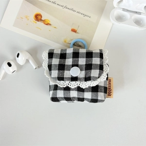 Detail of checkered earbud case with lace trim and blue clip on white desk background