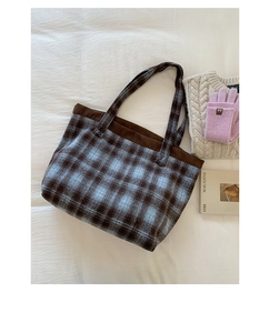 Detail of blue and brown plaid wool tote bag with corduroy trim on a white fabric background